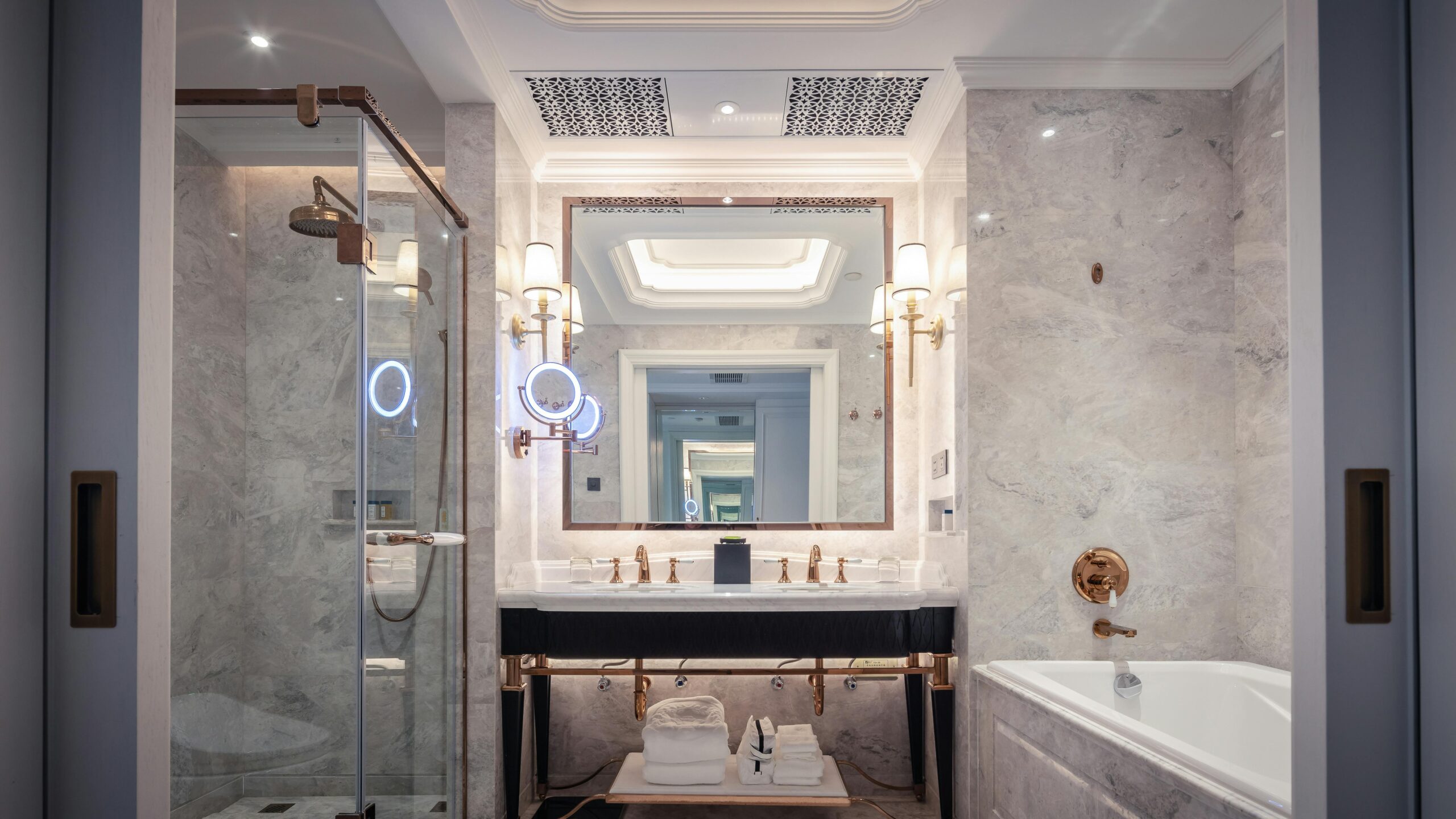 Elegant bathroom featuring a marble sink, bathtub, and mirror with ambient lighting.